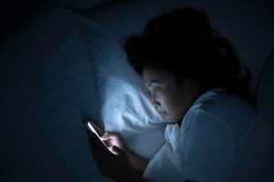 Woman scrolling on her phone while in bed