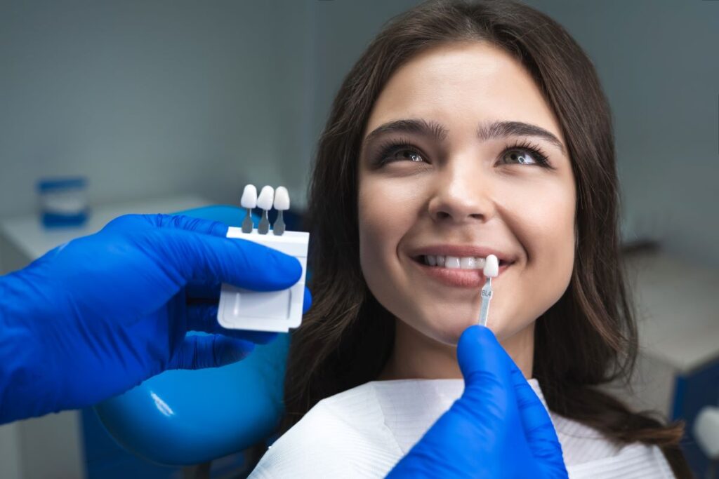 A woman seated in a dental chair selecting a shade of white for her new veneers.